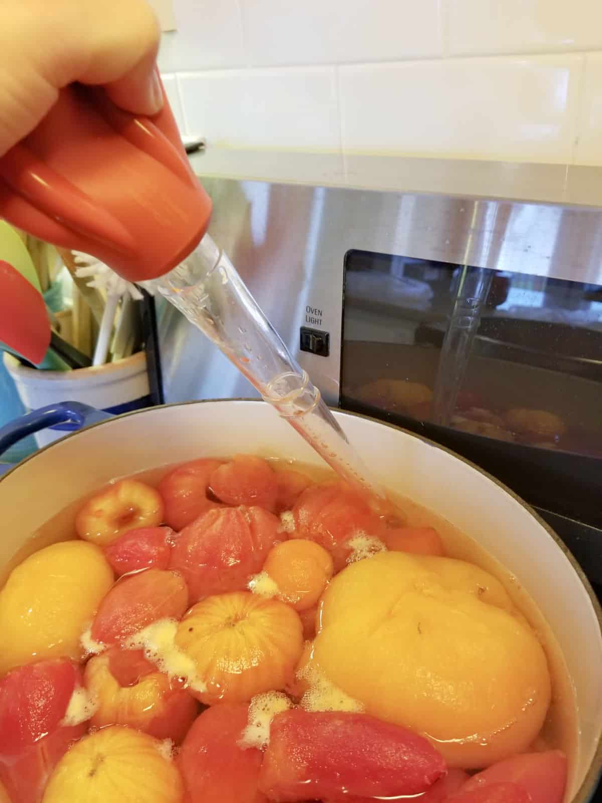 a turkey baster removing tomato water from bowl full of defrosting tomatoes