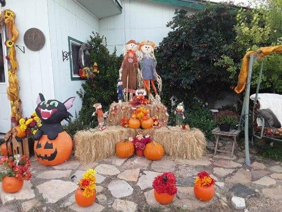 fall yard decorations with straw bales, scarecrows and pumpkins