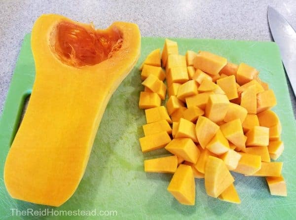 half a butternut squash and a pile of cubed butternut winter squash on a green cutting board - how to cook winter squash in an instant pot