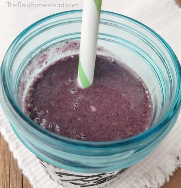 blueberry smoothie in a teal mason jar with a straw