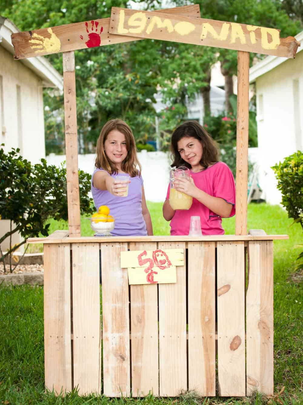 2 girls selling lemonade at their home made lemonade stand