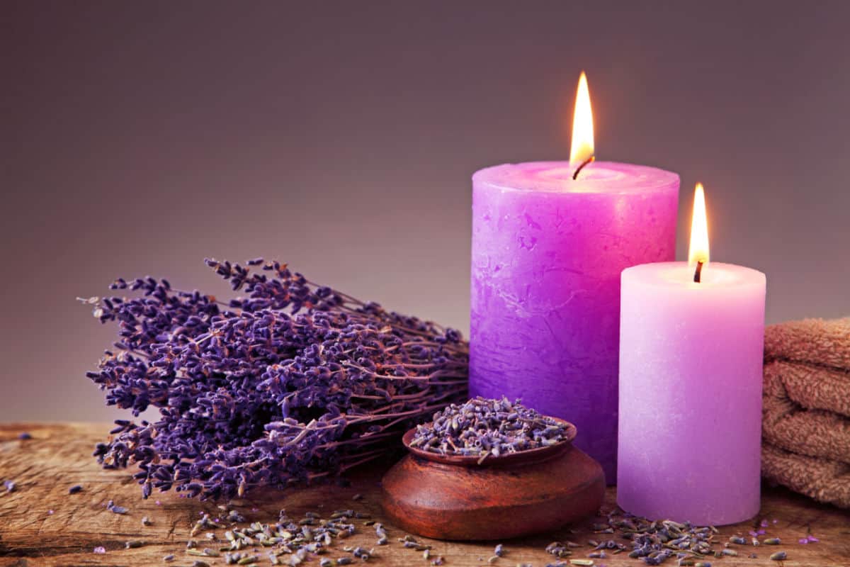 bunch of lavender with purple candles and bowl of lavender buds