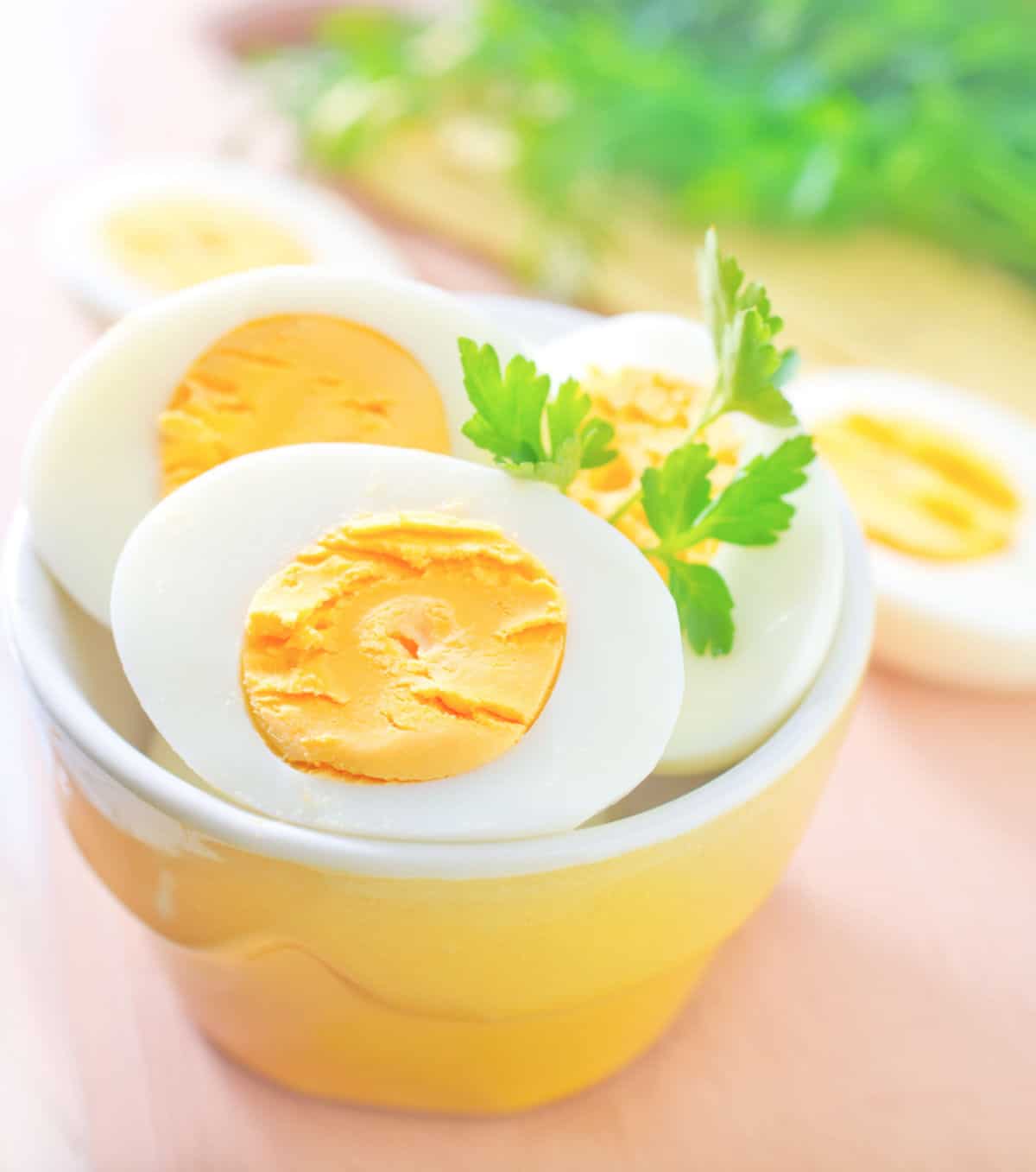 a small yellow bowl with halves of hard boiled eggs with parsely