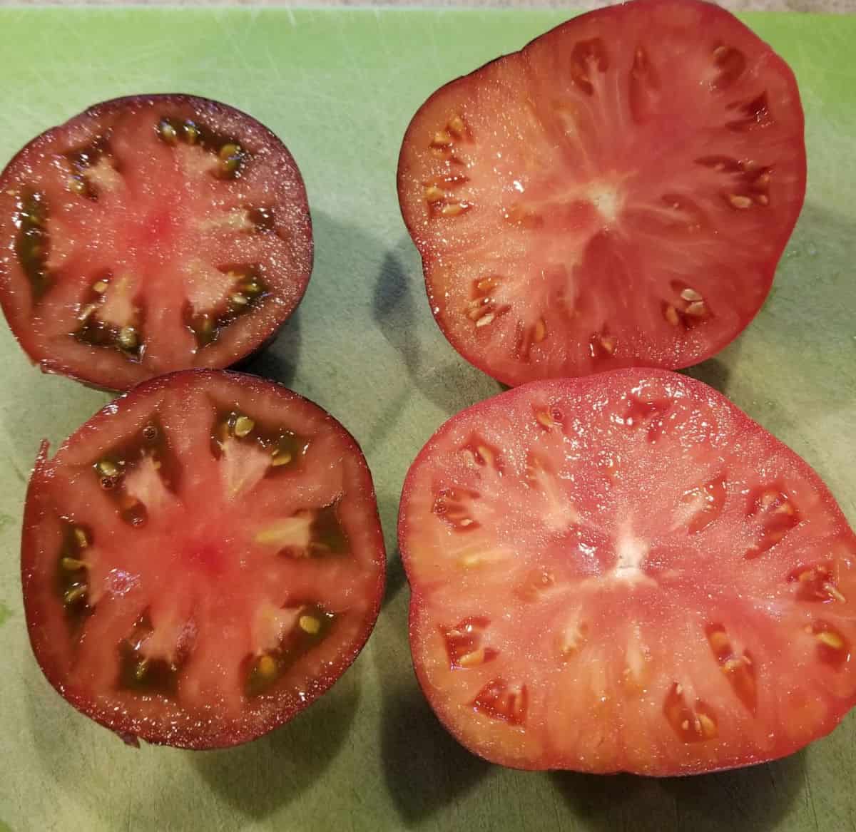sliced open black and blue beauty tomatoes showing the color of the flesh inside