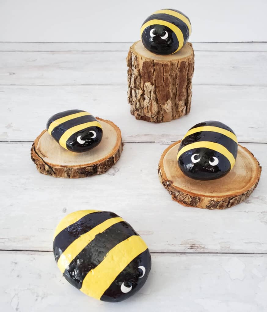 4 small painted bumble bee rocks mounted on wood branch slices