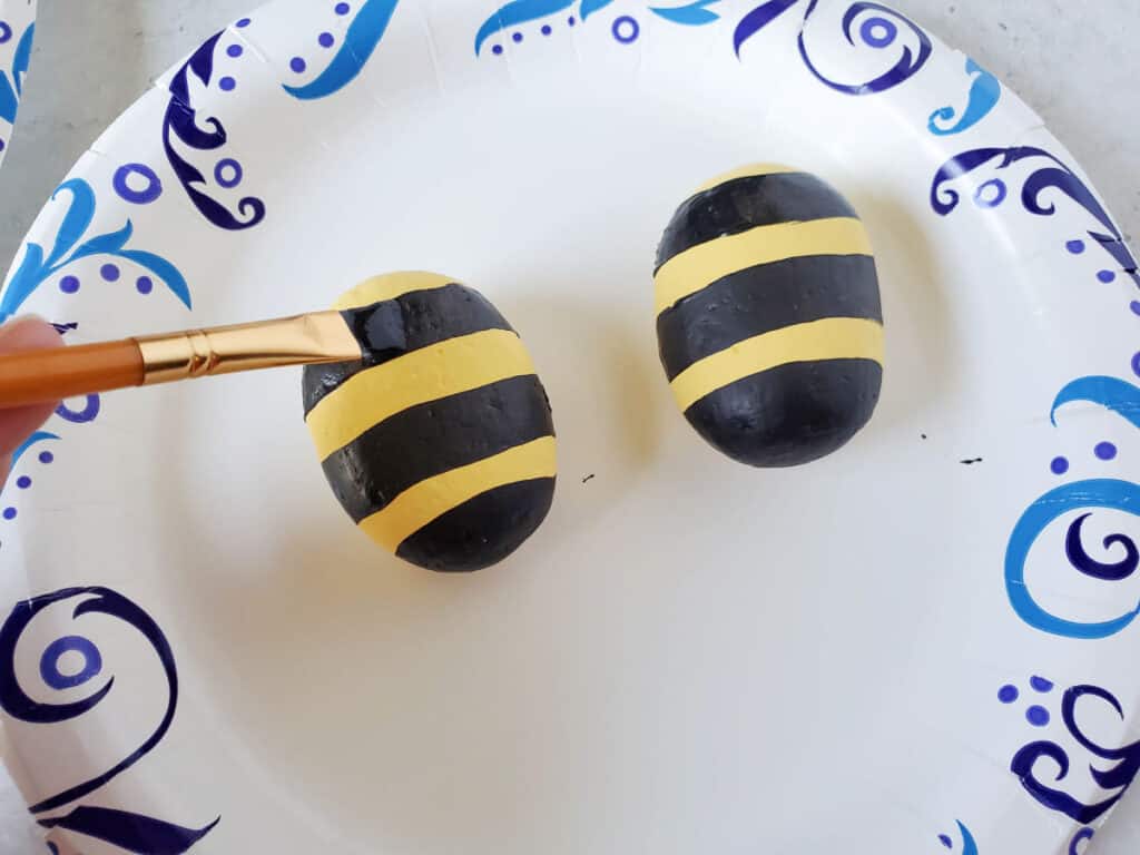 painting black stripes on the bumble bee rocks