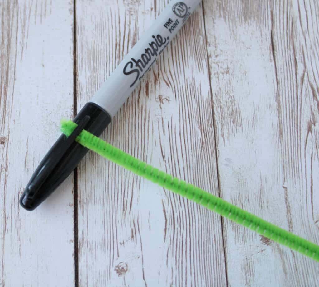 a permanent marker with the pipe cleaner fastened underneath the pocket clip on the pen cap
