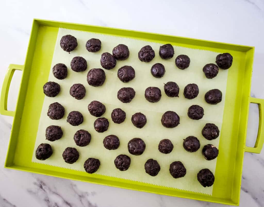 oreo cookie balls formed and placed on a sheet of parchment paper on a baking sheet