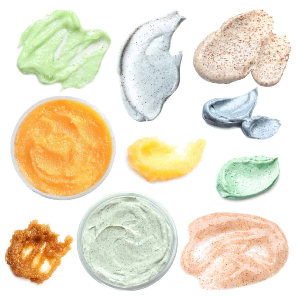 samples of assorted bath scrubs, in jars and smeared on a white background