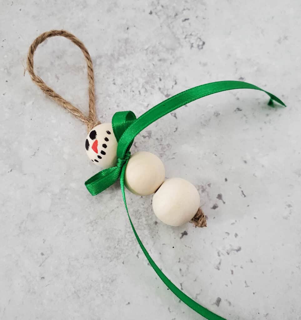 close up of the ribbon tied in a bow below the snowman's head bead
