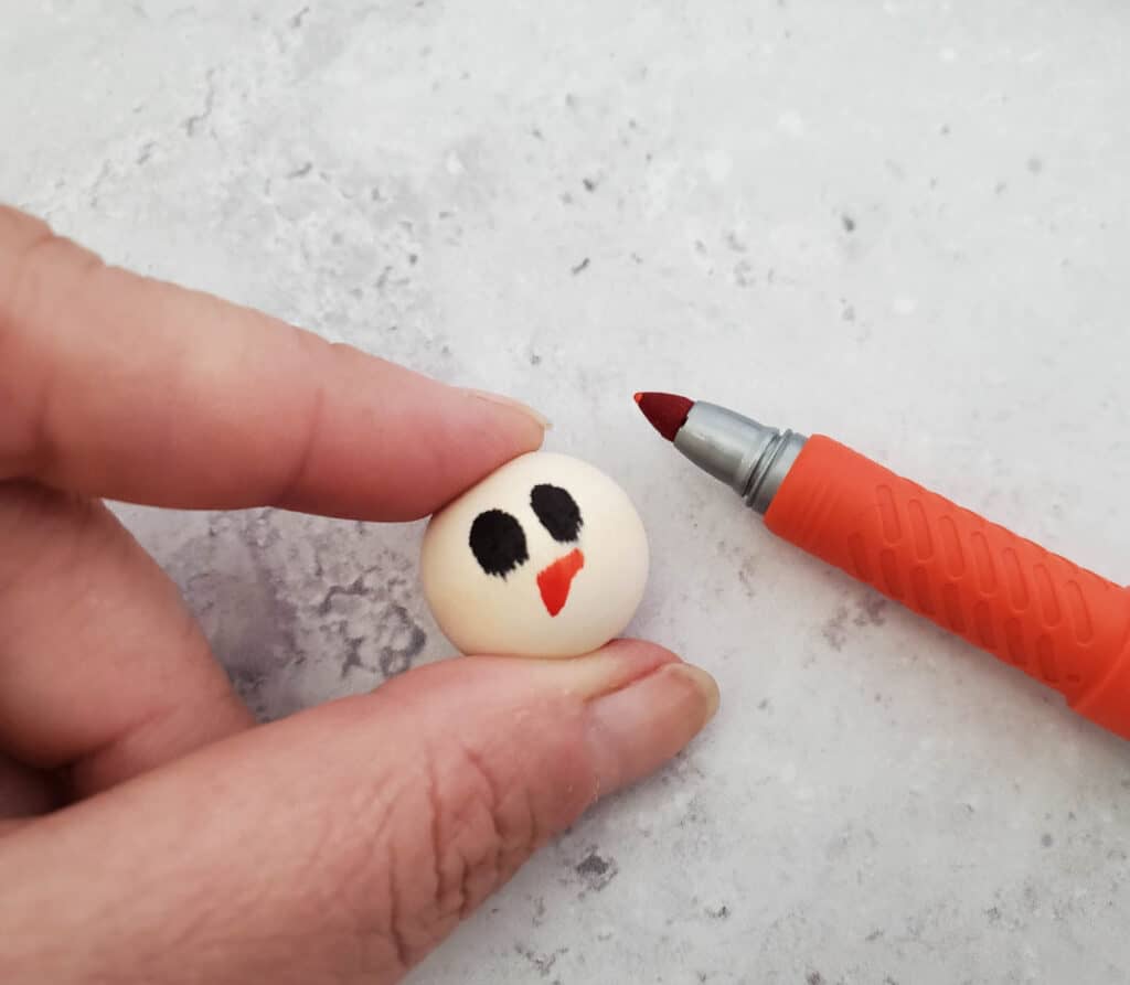 close up of drawing a snowman nose on a bead
