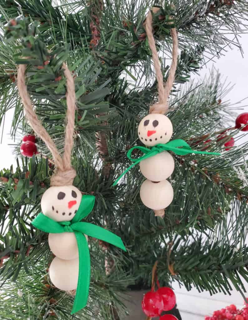 close up of two wood bead snowman ornaments hanging on a Christmas tree