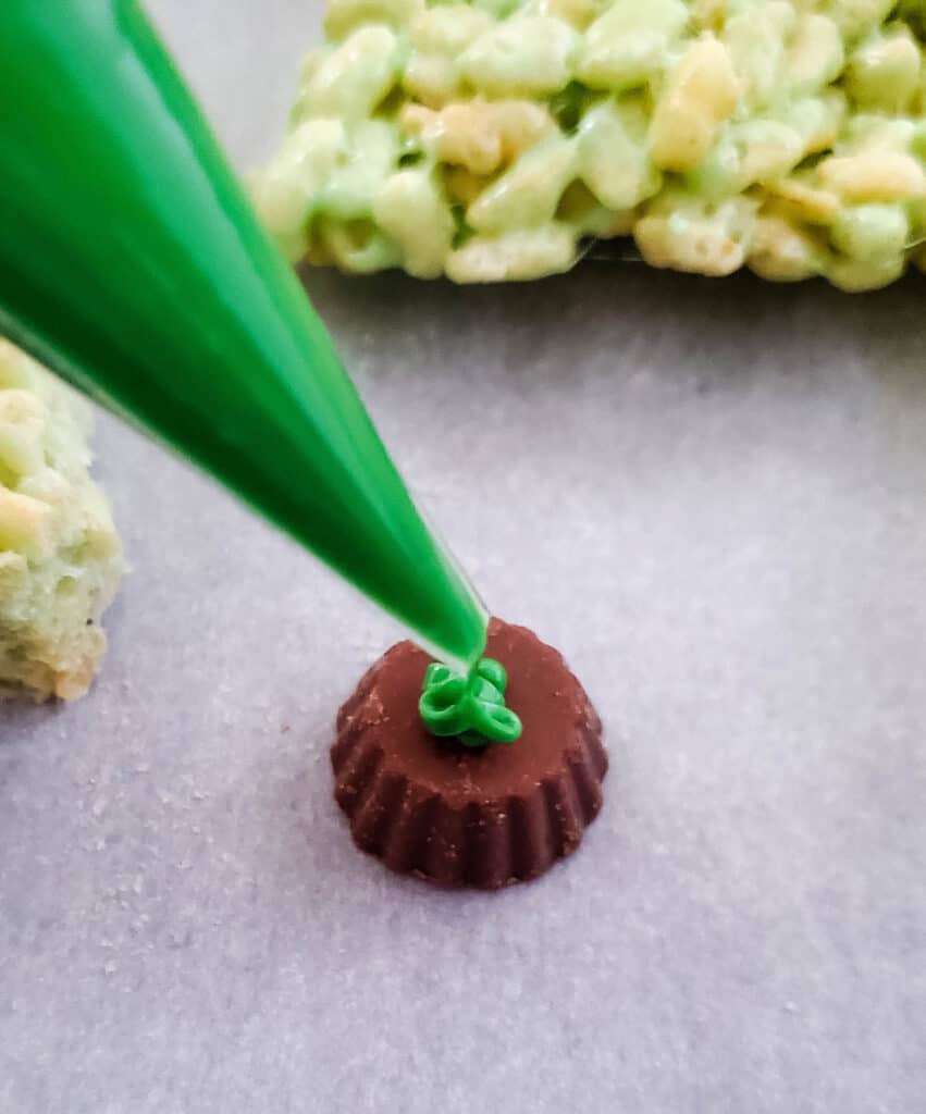 applying the melted green candy melts to the mini reese's peanut butter cup for the trunk of the tree