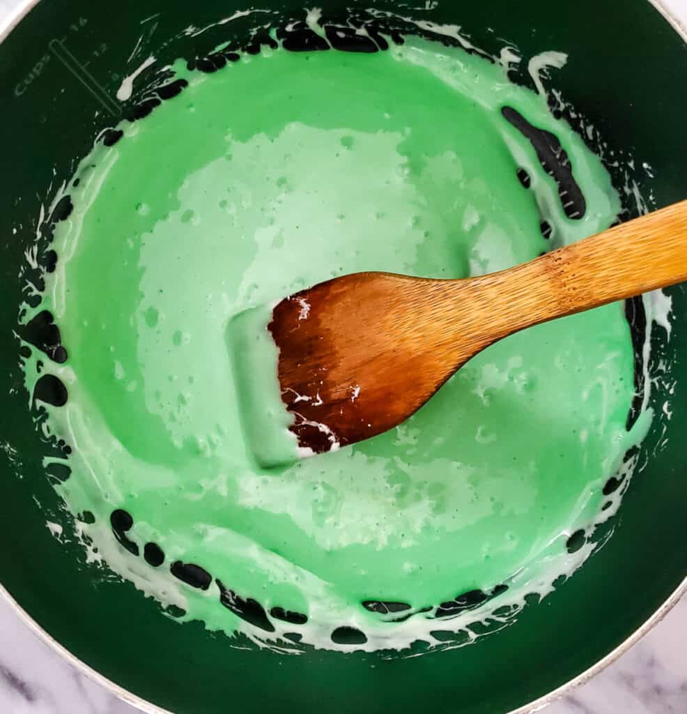 showing the stirred melted marshmallow mix with green food coloring stirred in to a solid green color