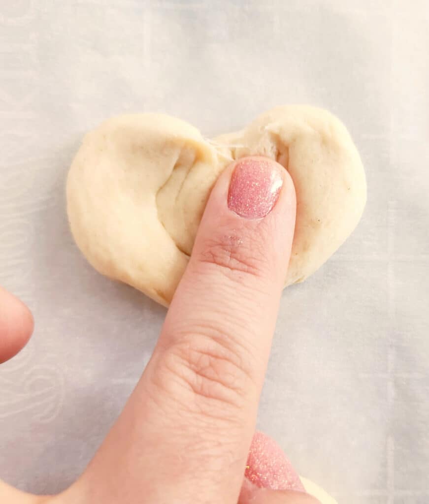 pressing the dough heart shapes flat with a finger