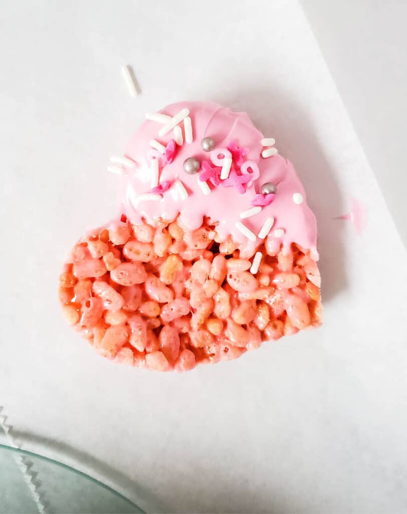 adding sprinkles to the wet melted candy wafer dipped side of the valentines rice krispie treats