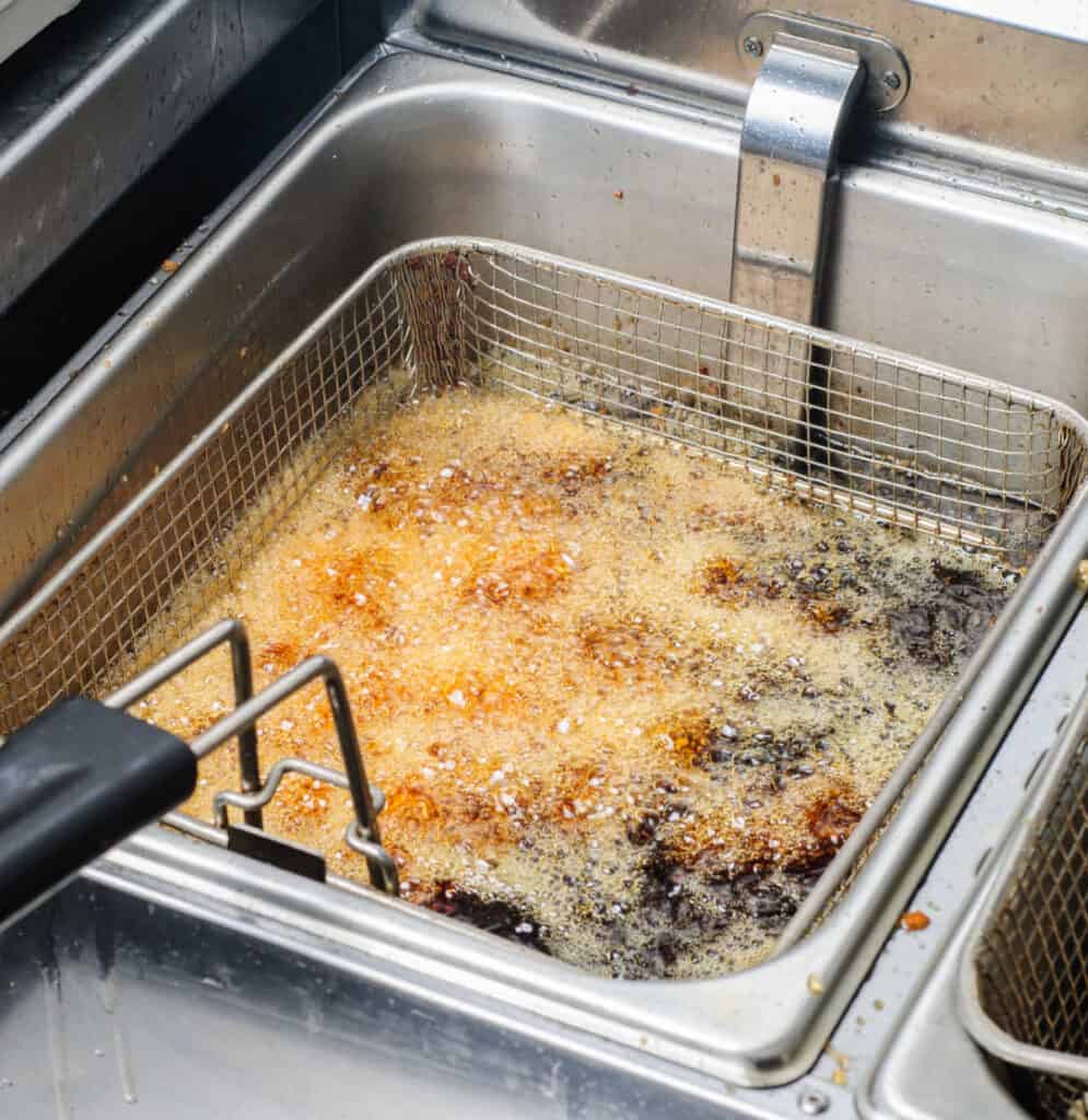 a commercial deep fryer full of oil frying food
