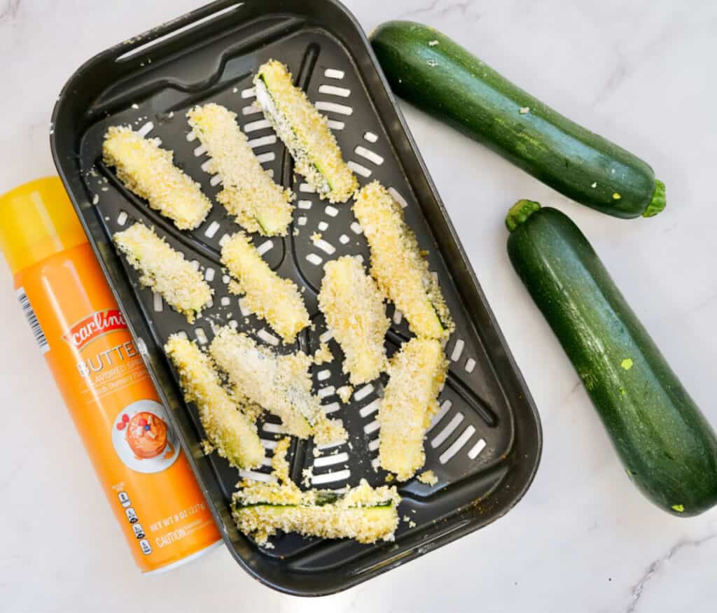 breaded zucchini fries place on air fryer baking sheet