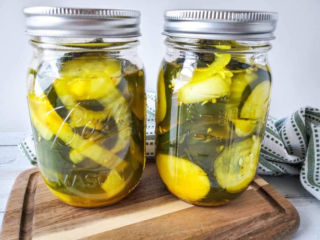 close up of two mason jars on wood cutting board full of no cook refrigerator pickles