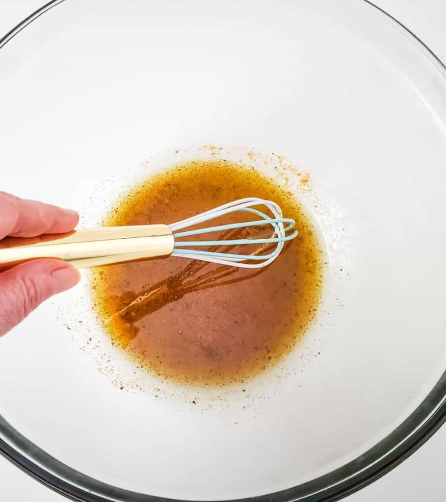whisking all of the dressing ingredients together in glass bowl