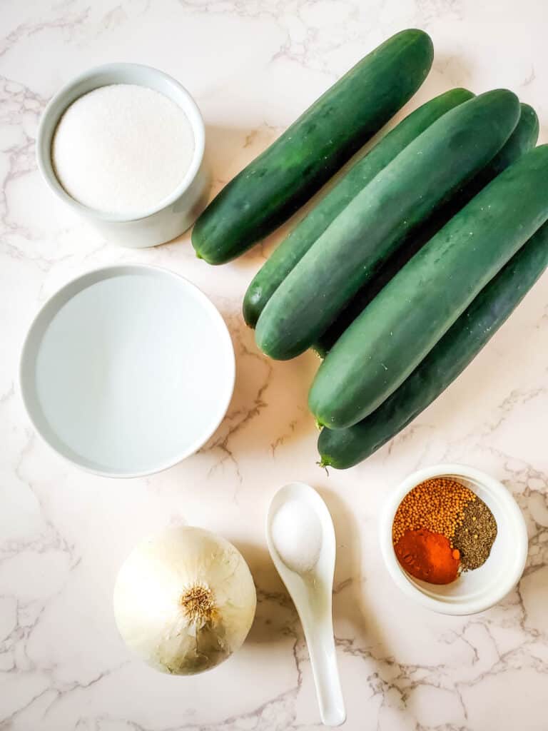 ingredients for no cook refrigerator pickles including cucumbers, onion, sugar, vinegar, salt and spices